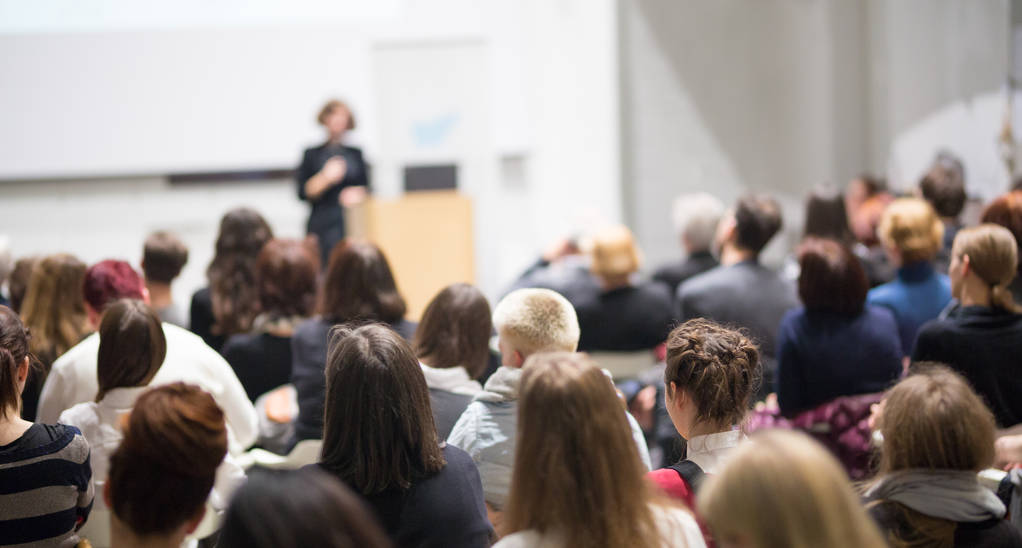 Woman giving presentation in lecture hall at university.